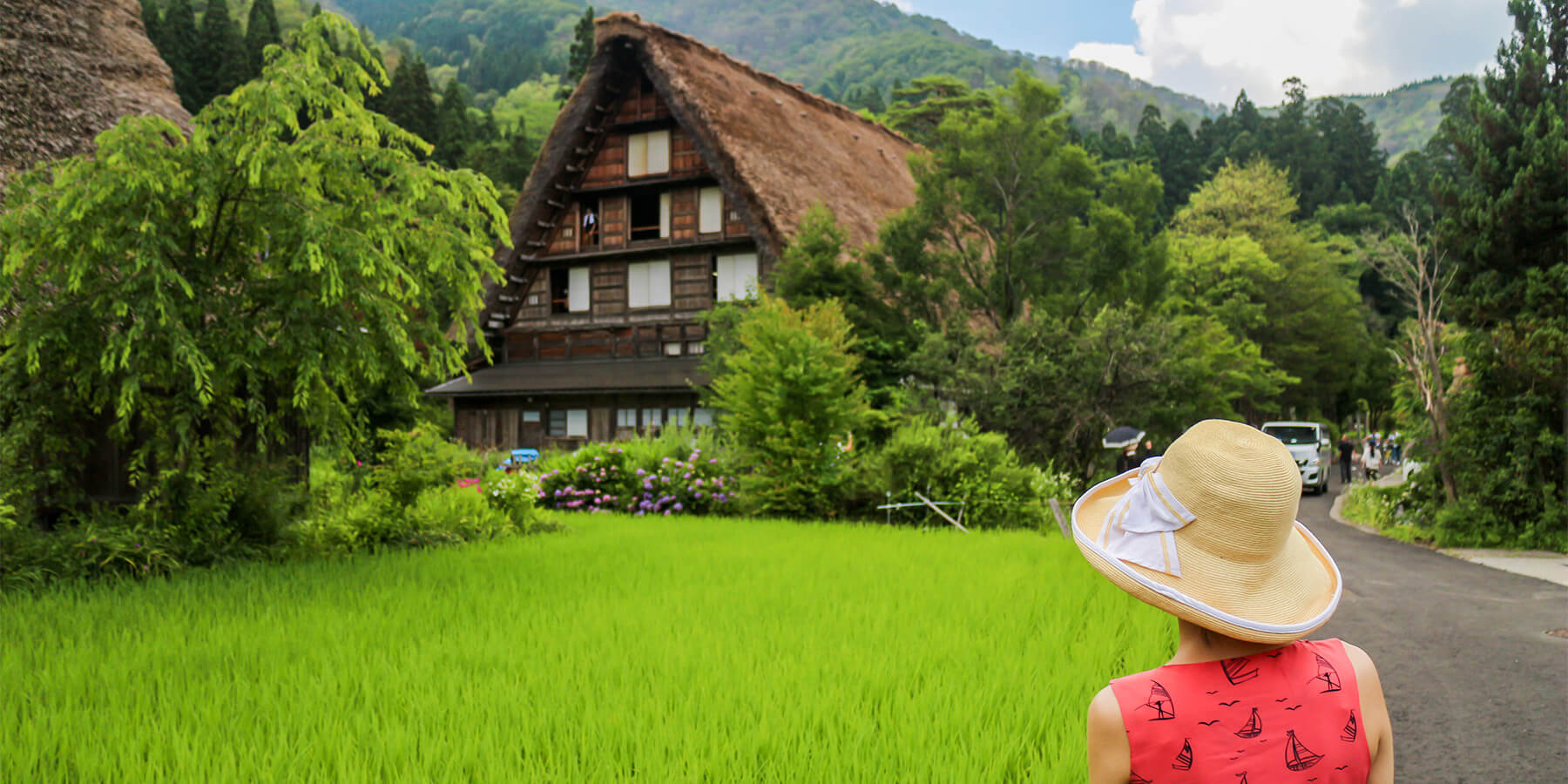Hida Highland in Japan - a woman in a red dress and a straw hat.
