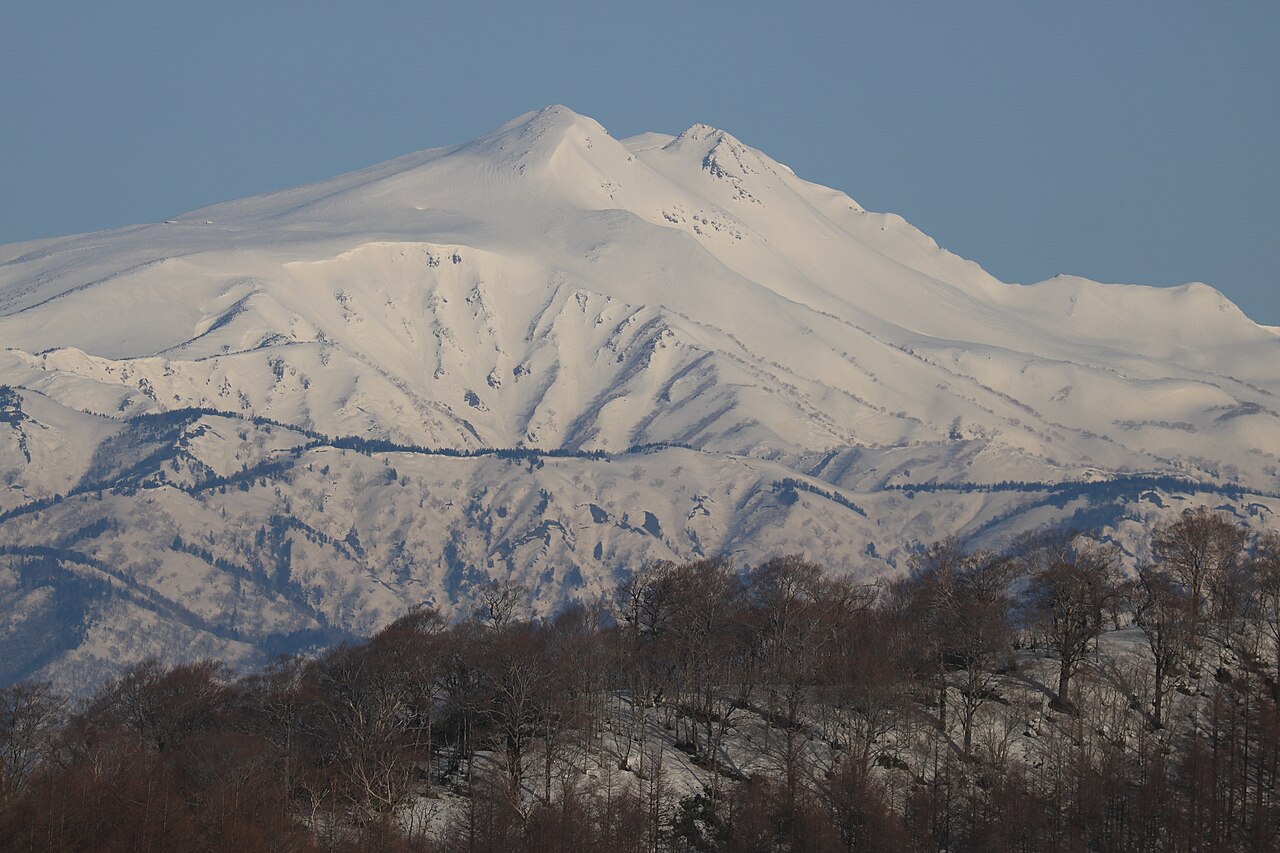 Hida Highland in Japan - a large mountain covered in snow with trees.
