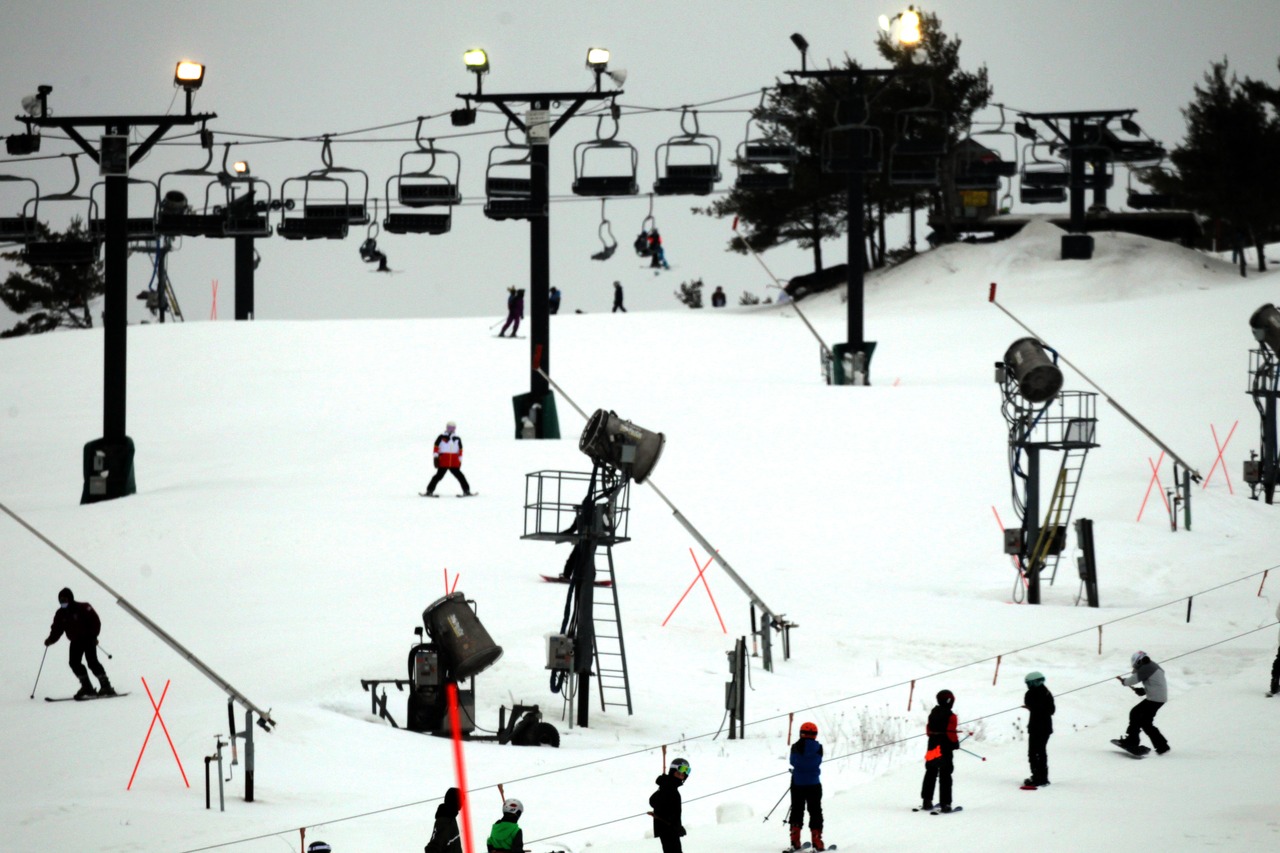 View of the wintry landscape at Brandywine ski resort in Northfield Ohio USA with ski lifts transporting winter sports enthusiasts up the snowy slopes. A chalet is seen in the backdrop.