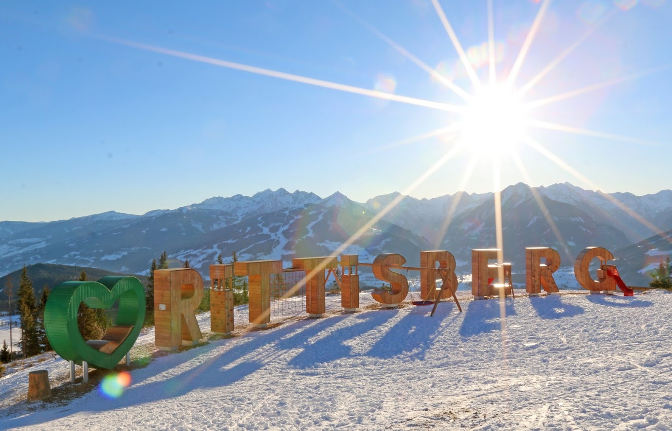 Rittisberg in Austria - the sun shines over the sign at the top of the mountain.