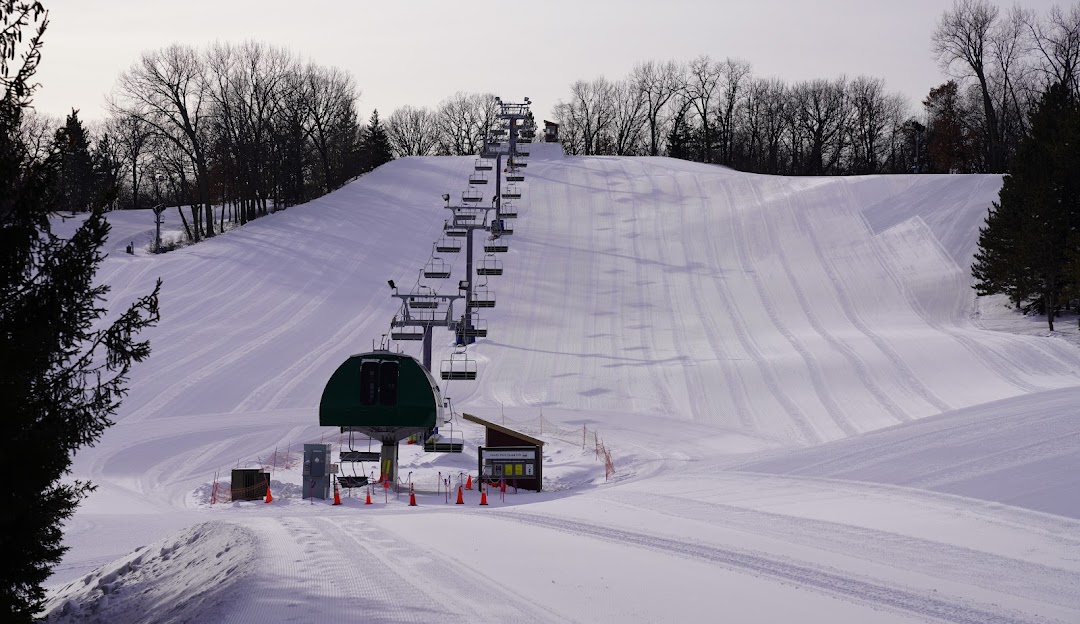 A vibrant scene at Hyland Hills ski resort in Minnesota featuring winter sports enthusiasts on snow-covered slopes with a ski lift in the background.