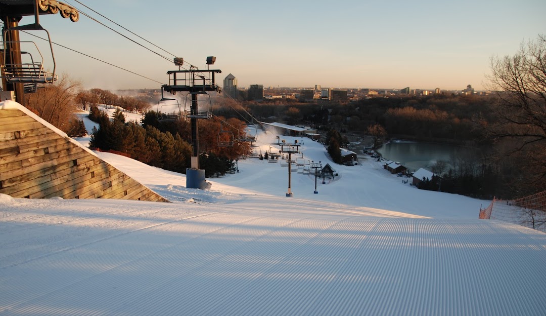 Winter scene at Hyland Hills, Minnesota featuring ski lifts and slopes dotted with skiers against the stunning backdrop of a snowy landscape. A beacon among ski resorts, the facility doubles as a winter sports centre.