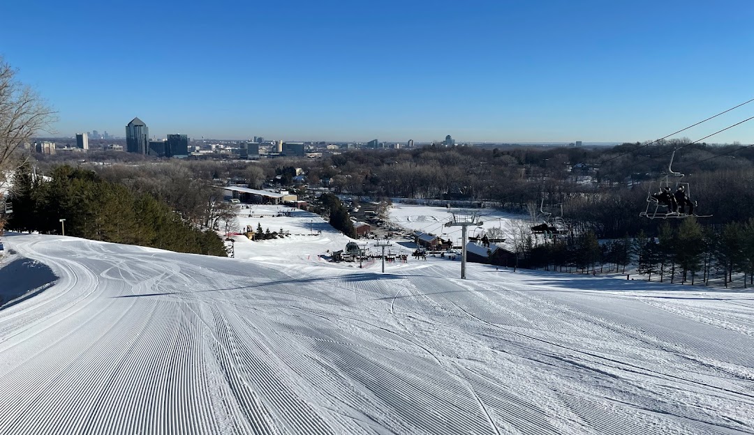 Winter scene at Hyland Hills, Minnesota showcasing a bustling ski resort complete with snow-covered slopes, a busy ski lift, and an active skier enjoying the snowy thrills.