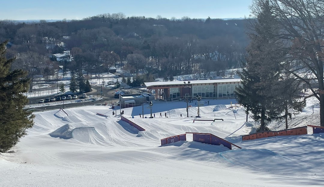 Winter panorama at Hyland Hills, Minnesota, featuring a bustling ski resort, abundant snow-covered slopes, and adventurous skiers enjoying winter sports.