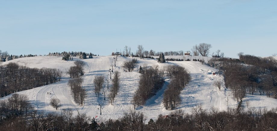 Winter scene at Bear's Den Mountain in North Dakota, USA, featuring a lively ski resort. Snow-covered slopes, a cosy chalet, and a ski lift can be seen, evoking a sense of adventure and tranquillity.