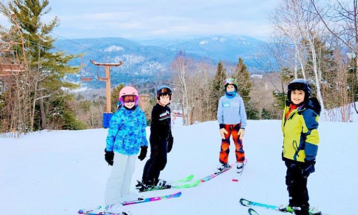 Campton Mountain in USA - a group of kids standing on top of a snow covered slope.