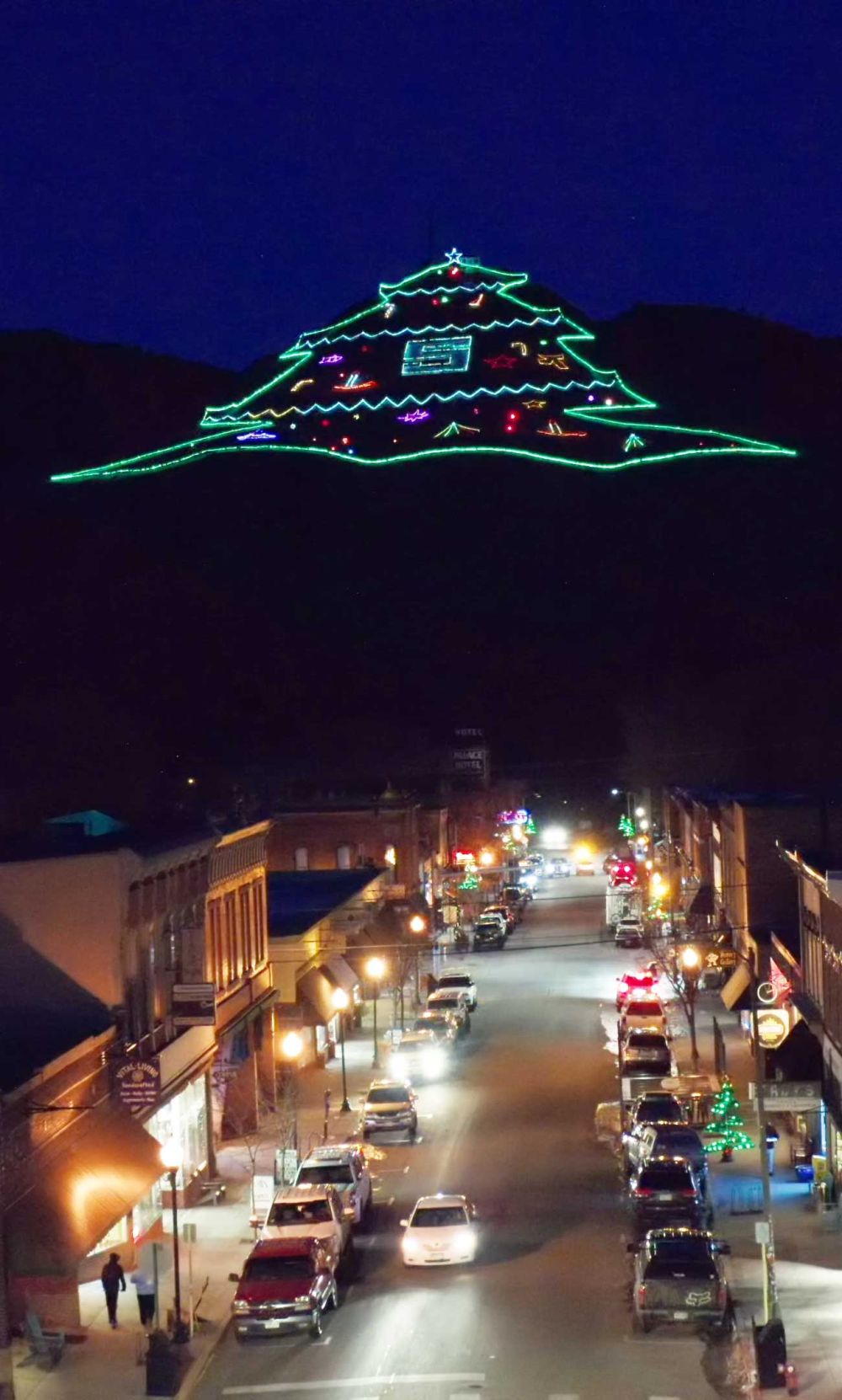 Christmas Mountain in USA - a city street at night with cars parked on the side.