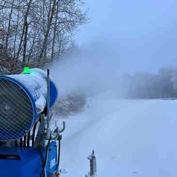 Christmas Mountain in USA - a snow blower sitting on top of a snow covered field.