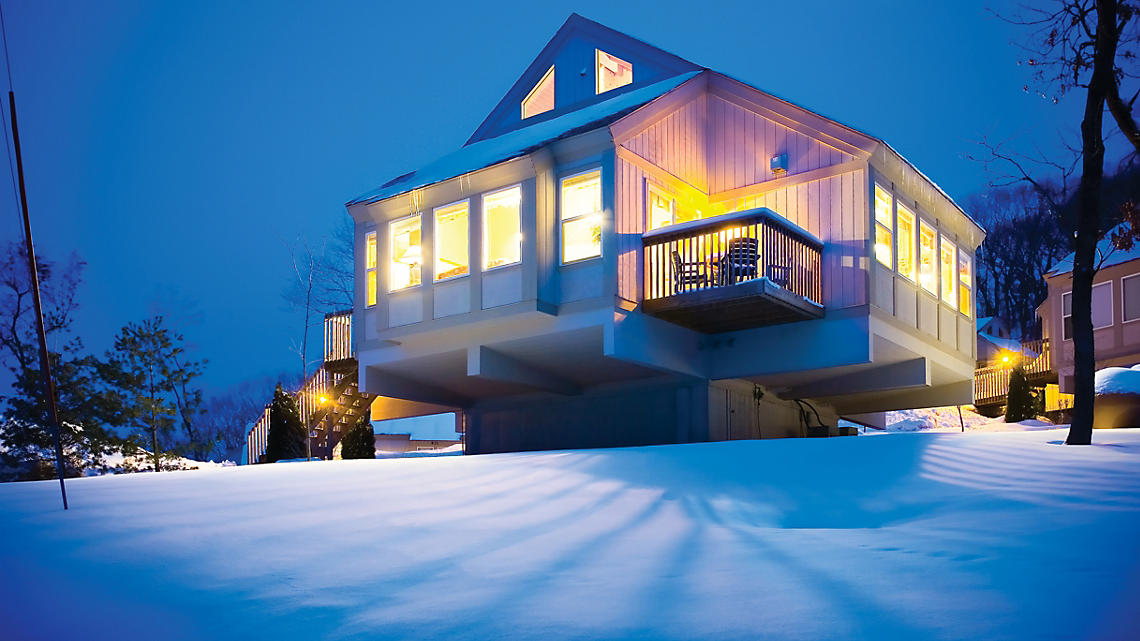 View of Christmas Mountain in Wisconsin, featuring a charming chalet nestled amidst a beautiful winter scenery with a snow-covered landscape and the glow of a ski resort in the distance.