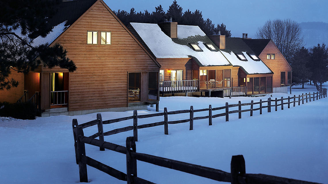 Image of a beautiful winter scenery at Christmas Mountain, Wisconsin, USA. A lodge is seen in the foreground, presumably part of a winter sports centre. The landscape showcases the serene beauty of winter sports scenes.