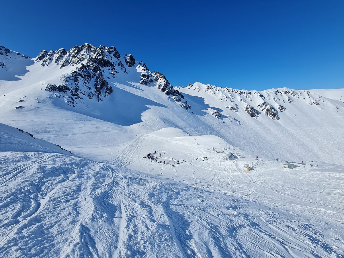 Mount Olympus in New Zealand - a group of people skiing down a snowy mountain.