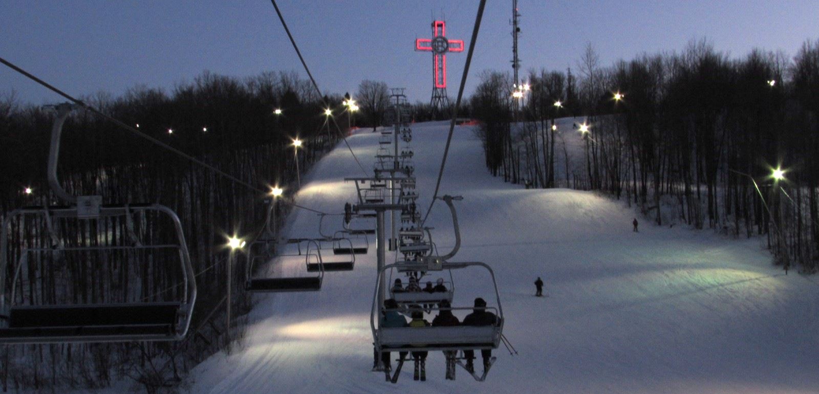 View of Mont Bellevue ski resort in Estrie Quebec featuring a busy winter sports scene with a ski lift and skiers taking to the slopes.