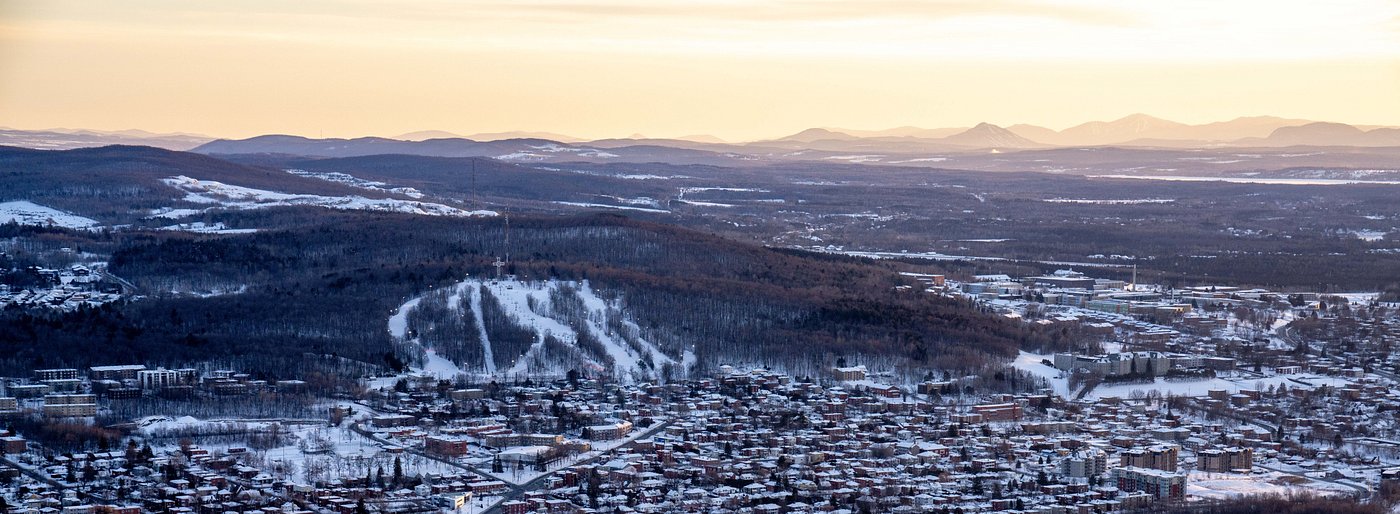 View of the bustling Mont Bellevue ski resort in Estrie, Quebec, Canada, featuring a ski lift and snow-covered slopes filled with winter sports enthusiasts.