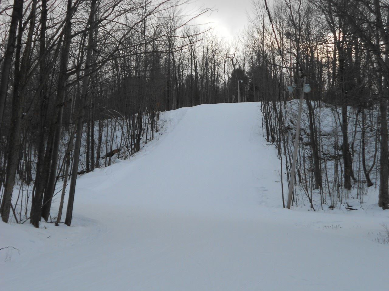 A skier enjoying a winter day on the slopes of Mont Bellevue ski resort in Estrie Quebec Canada. A ski lift and a charming chalet peek through the snowy landscape.