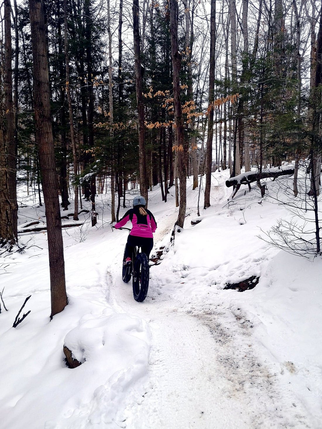 Winter sports scene at Mont Bellevue, Quebec, showcasing a mountain bike near a chalet, a skier trailing through the snowy terrain, nestled amidst stunning winter scenery.