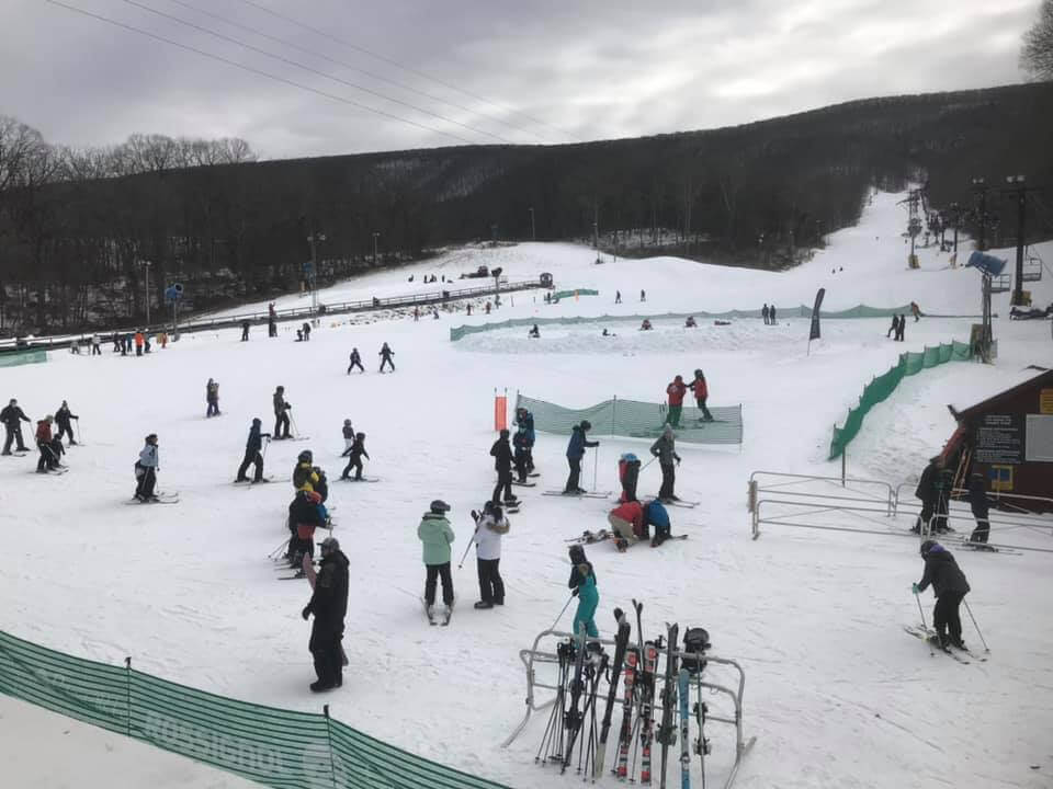 Winter scene at The Omni Homestead ski resort in Virginia, USA, featuring a skier descending on snow-covered slopes and a ski lift in the background.