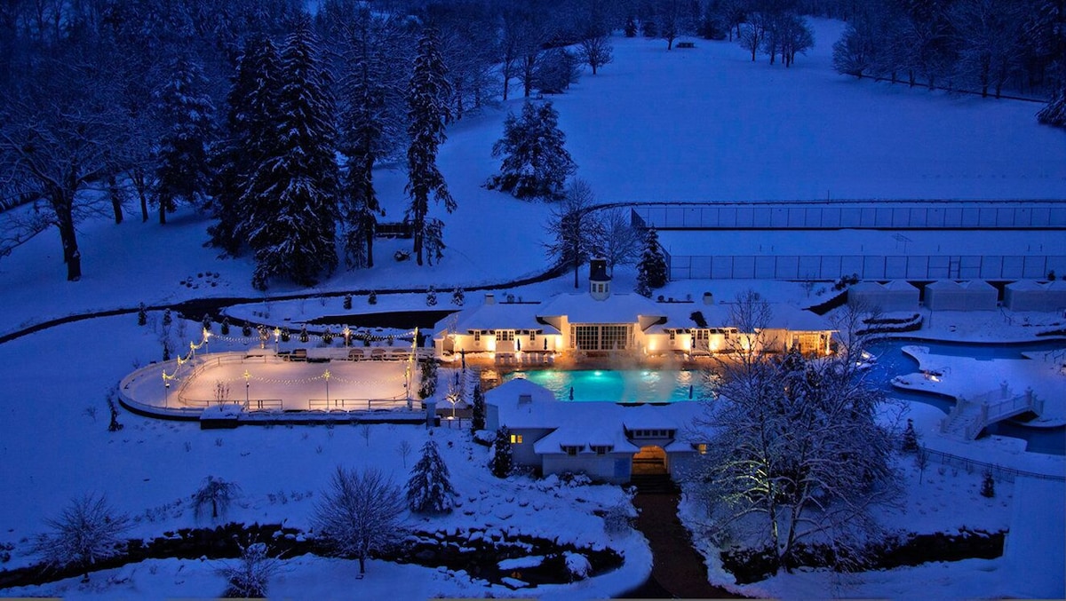Winter scene at The Omni Homestead, Virginia, showcasing a charming chalet set amid a stunning snowy landscape, indicative of a bustling ski resort and winter sports center.