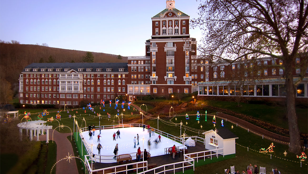 Winter scene at The Omni Homestead in Virginia showcasing a bustling winter sports center at a ski resort with a charming lodge nearby, surrounded by stunning winter scenery.