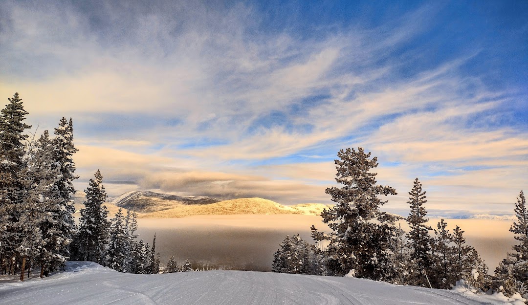 Kimberley in Canada - a snow covered mountain with trees and clouds in the background.
