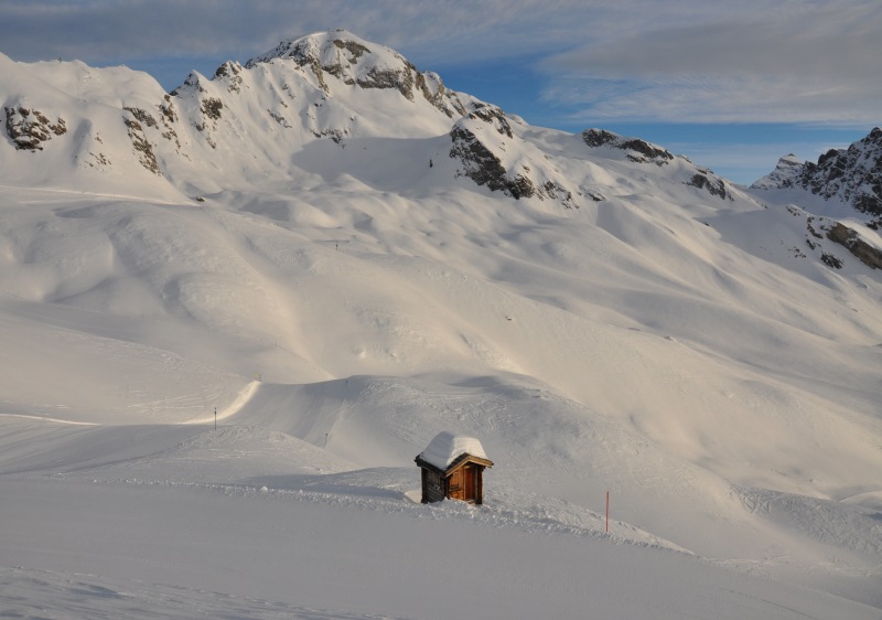 A picturesque view from Lauchernalp – Lötschental in Switzerland featuring a mountain hut nestled amidst a bustling ski resort sprinkled with charming chalets and winter sports enthusiasts.