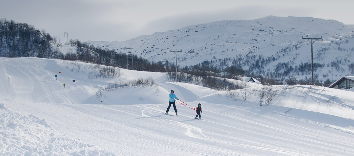 Fidjeland in Norway - two people are skiing down a snowy hill.