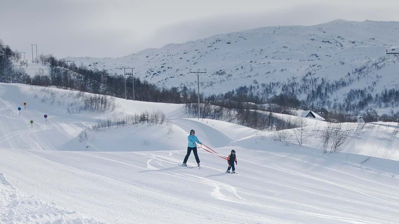 Fidjeland in Norway - two people are skiing down a snowy hill.
