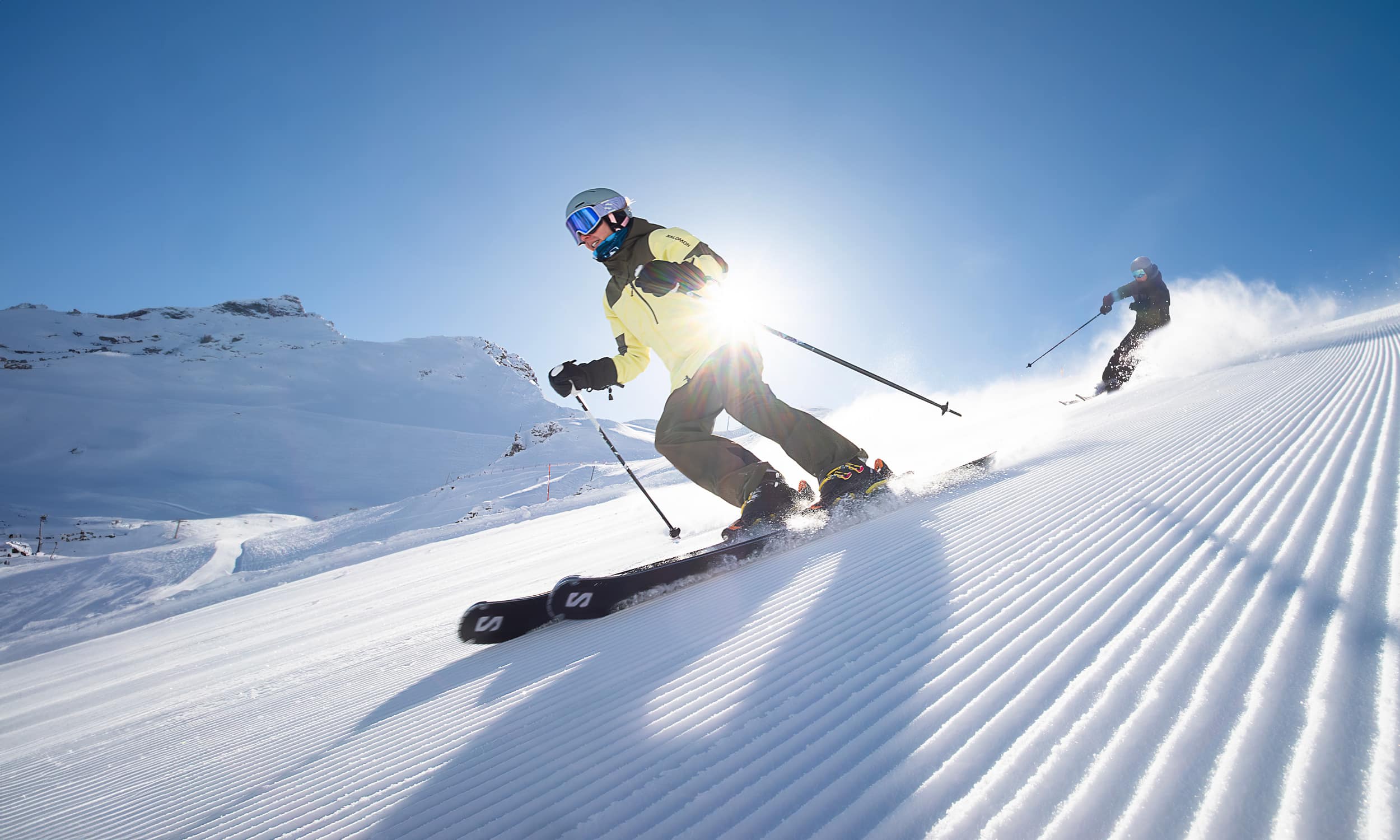 A skier gracefully glides down the snowy slopes of Val Cenis in Savoie Mont Blanc France. In the backdrop shrouded beneath a winter sky stands a cozy chalet. Nearby a group of people engage in winter sports.