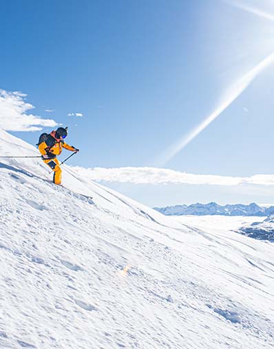 A skier and a snowboarder enjoying a winter sports activity at the ski resort in Val Cenis, Savoie Mont Blanc, France, with a cozy chalet nestled in the snowy landscape.