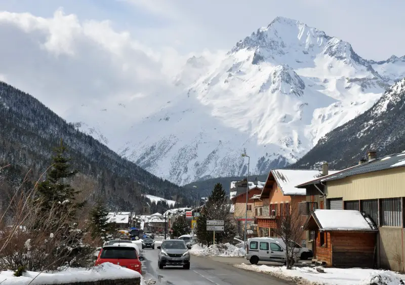 Scenic view of Val Cenis ski resort in Savoie, France, featuring a prominent chalet amidst breathtaking winter scenery with distant mountains.