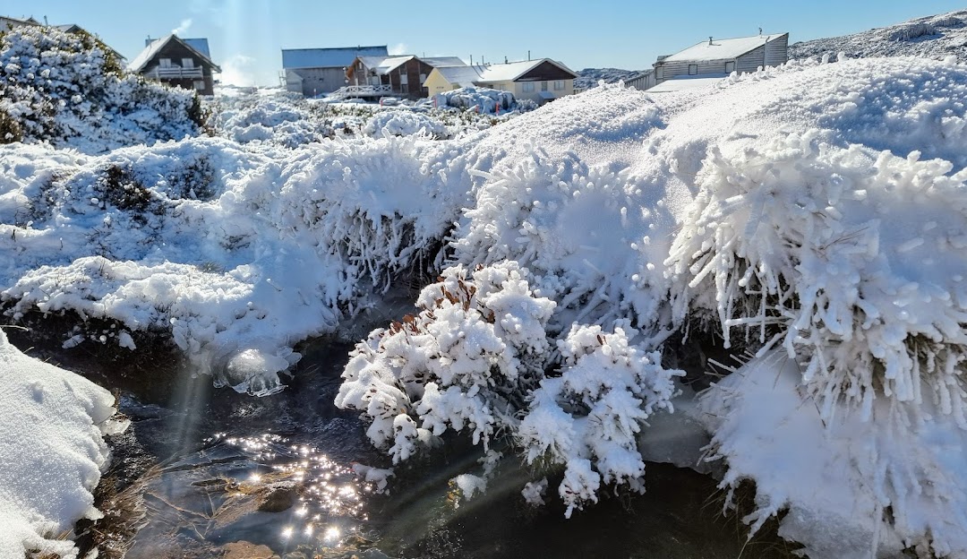 Winter scene at Ben Lomond, Tasmania showcasing a snow-covered landscape, a chalet in the distance, with hints of winter sports activities taking place.