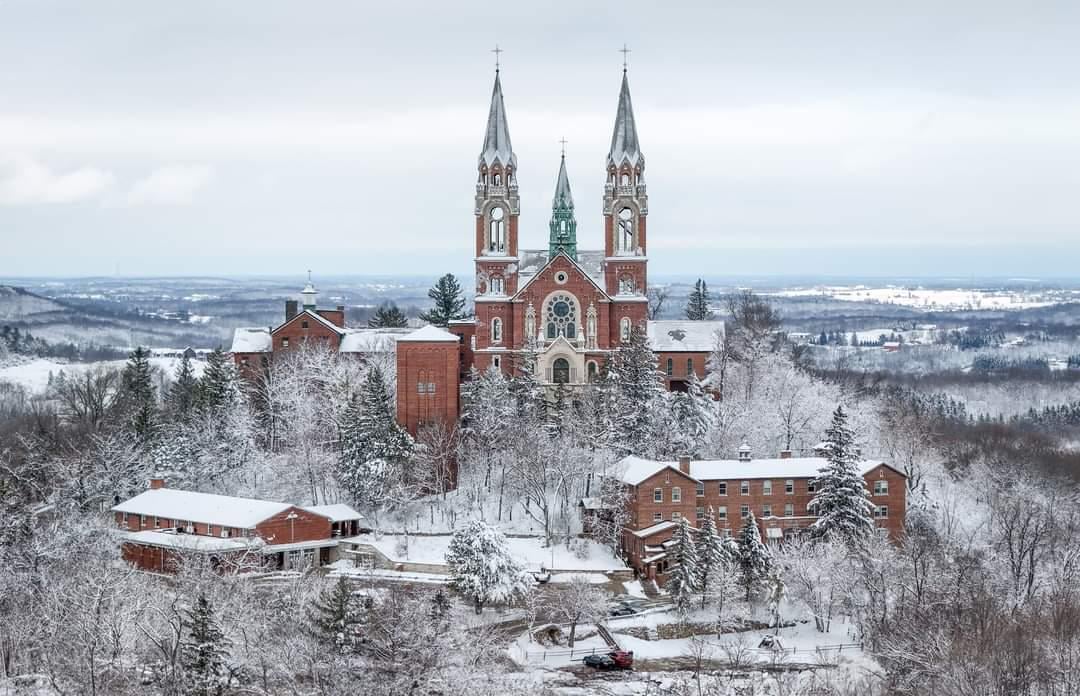 Winter sports enthusiasts enjoy the snow-covered slopes at Heiliger Huegel in Wisconsin, amidst a stunning winter landscape with a cozy chalet and bustling winter sports centre viewable.