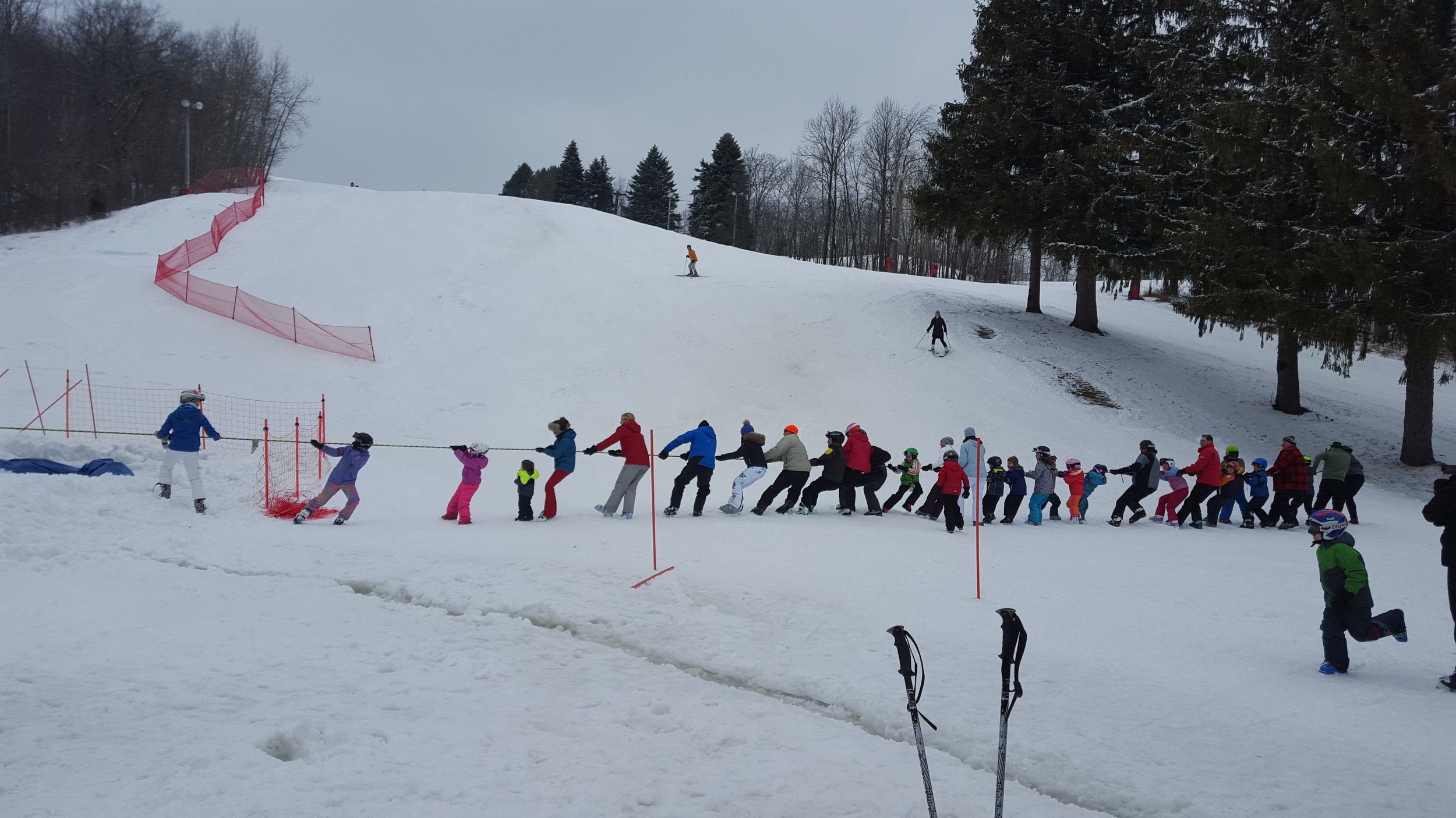 Winter scene at Heiliger Huegel Hubertus Wisconsin featuring a group of people skiing structures indicative of a winter sports center and a challet.