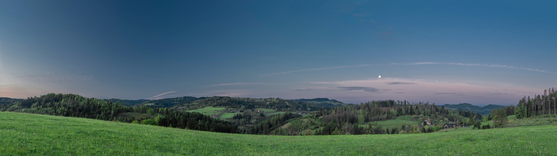 Vranča in Czech Republic - a green field with trees and mountains in the background.