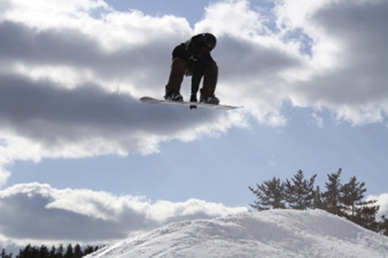 A snowboarder skillfully navigating the snowy slopes of Mystery Mountain in Manitoba, Canada. The pristine white snow around adds to the thrilling ambiance of the outdoor sport scenario.