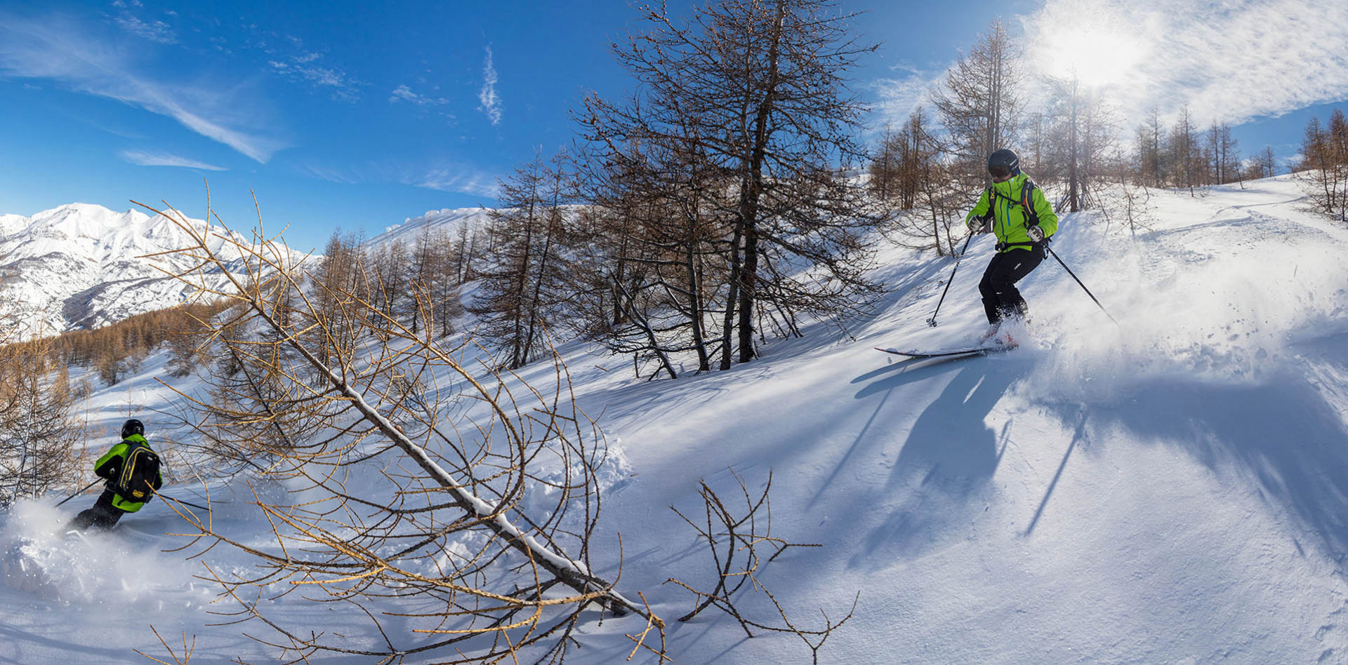 A skier and a snowboarder enjoying a winter sports scene at Val d'Allos - Espace Lumière in France, amid picturesque winter scenery with a charming chalet nearby.