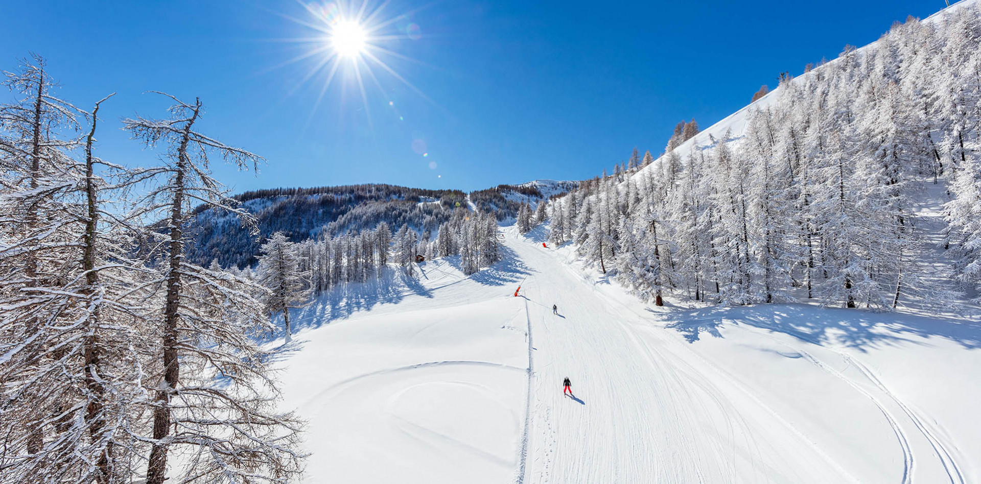Winter sports scene at Val d'Allos ski resort in France, featuring a skier gliding down snow-covered slopes, a chalet in the background and a ski lift nearby.