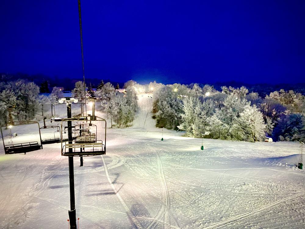 A picturesque view of Swiss Valley Ski Resort in Michigan USA featuring a ski lift amidst a beautiful winter sports scene surrounded by snowy landscape and a charming chalet.