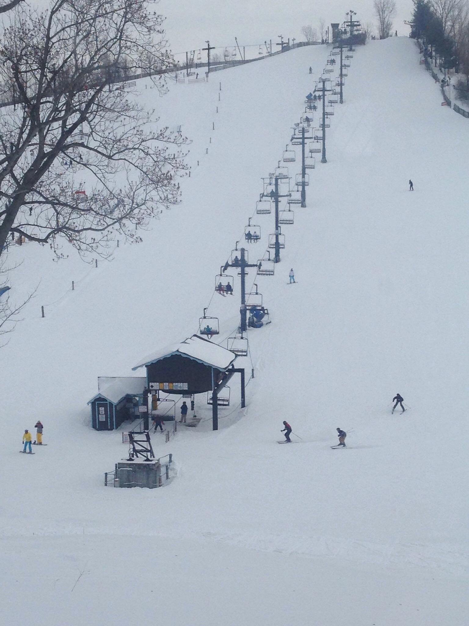 A winter scene at Swiss Valley ski resort in Michigan featuring a ski lift skiers enjoying winter sports and a picturesque snowy landscape.