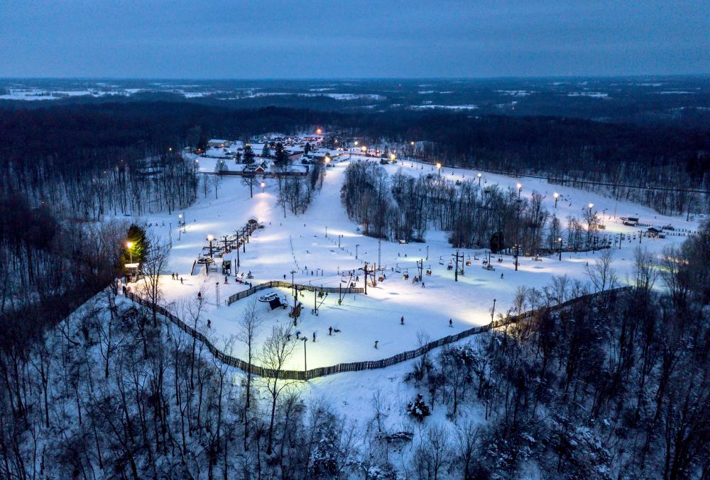 Winter sports enthusiasts enjoy a day at the Swiss Valley Ski Resort in Michigan, USA, featuring visible ski lifts amidst beautiful snow-covered scenery.