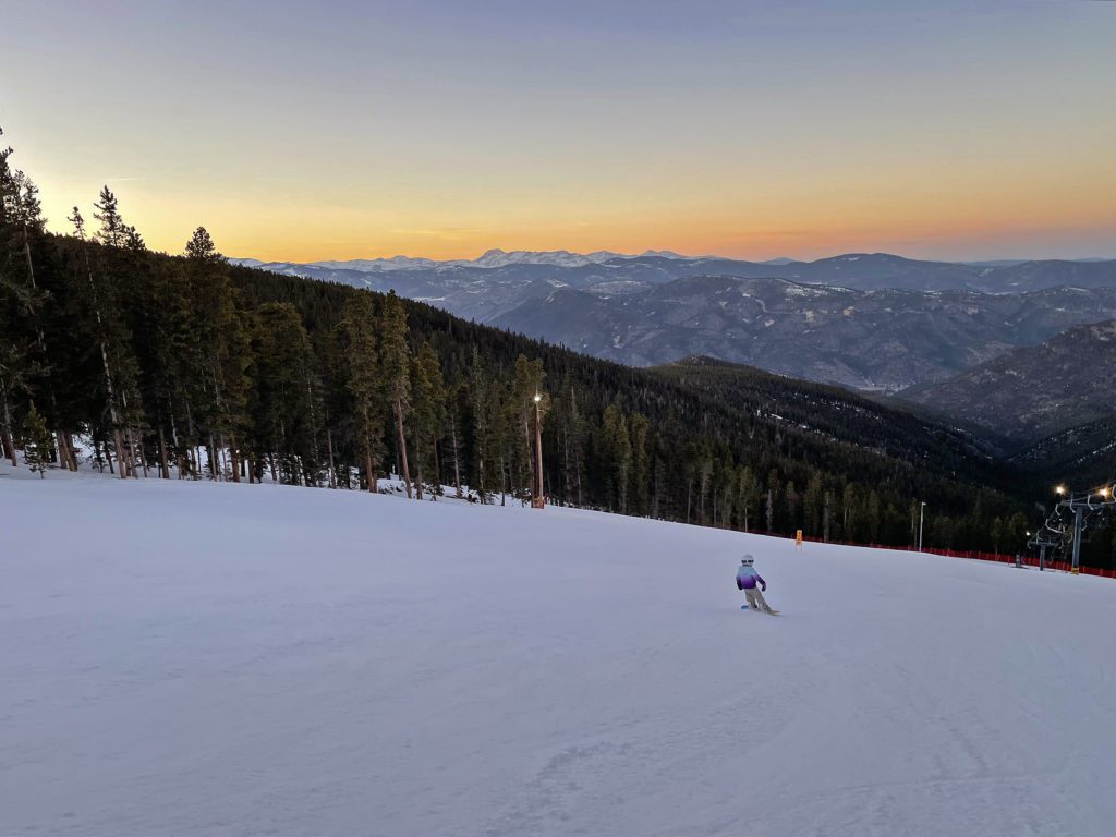 Echo Mountain Park – Idaho Springs in USA - a person skiing down a snowy slope at sunset.
