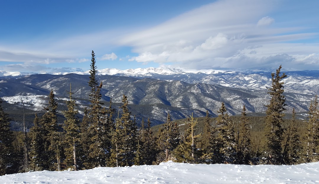 Winter sports scene at Echo Mountain Park in Idaho Springs, Colorado, featuring a ski resort nestled within snow-covered slopes of a towering mountain.