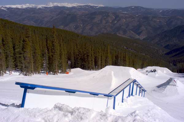 A bustling winter sports centre at Echo Mountain Park in Colorado featuring a vibrant winter sports scene which includes a ski resort. Visible participants engage in various activities such as snowmobiling and snowboarding.
