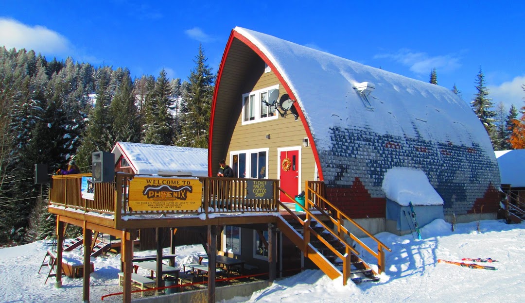 A picturesque scene at Phoenix Mountain ski resort in Kootenay Rockies Canada showcasing a bustling winter sports centre a rustic lodge and a mountain hut amidst a winter sports landscape.