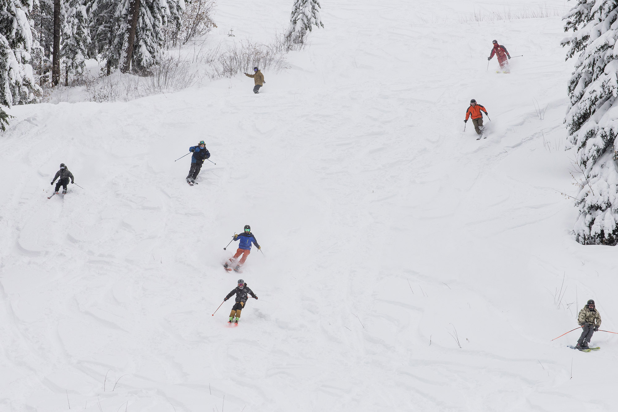 A group of skiers enjoying a beautiful day on the slopes of Phoenix Mountain in the Kootenay Rockies, British Columbia, Canada. This lively winter sports scene encapsulates the joy of family skiing at the ski resort.