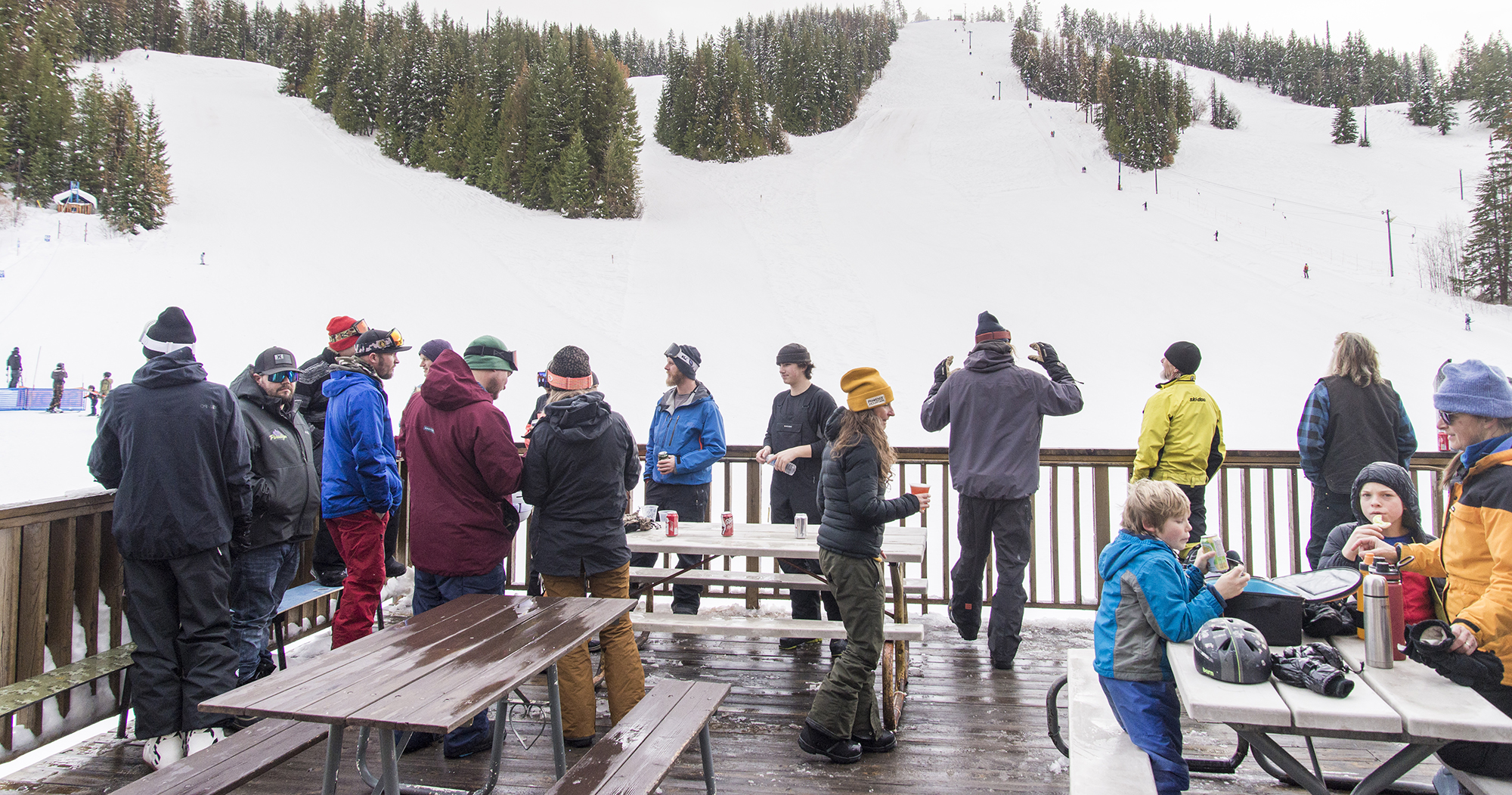 Winter sports enthusiasts enjoying a day of skiing at Phoenix Mountain Ski Resort in Kootenay Rockies, British Columbia, Canada. The ski lift running in the background adds to the lively ambiance.