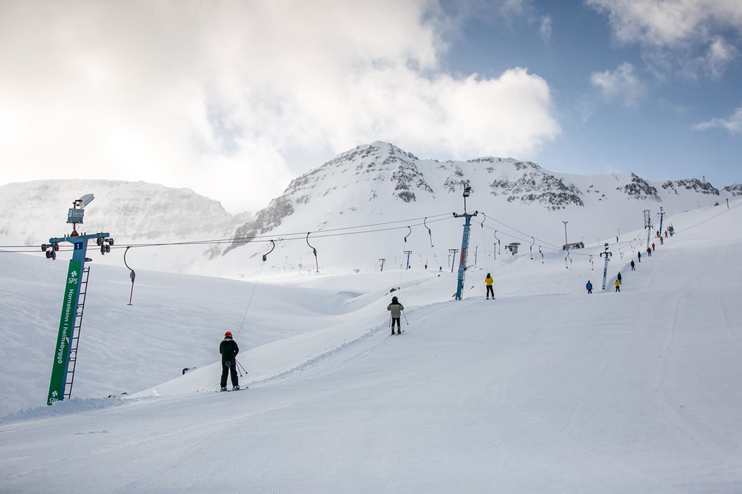 Skarðsdalur – Siglufjörður in Iceland - a group of people skiing down a snow covered mountain.