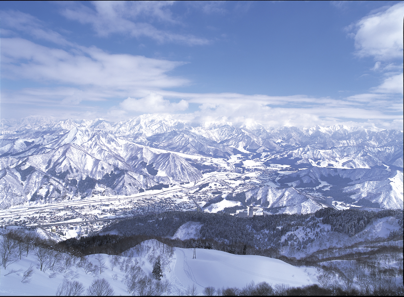 Ludens Yuzawa in Japan - a view of snow covered mountains from a mountain top.