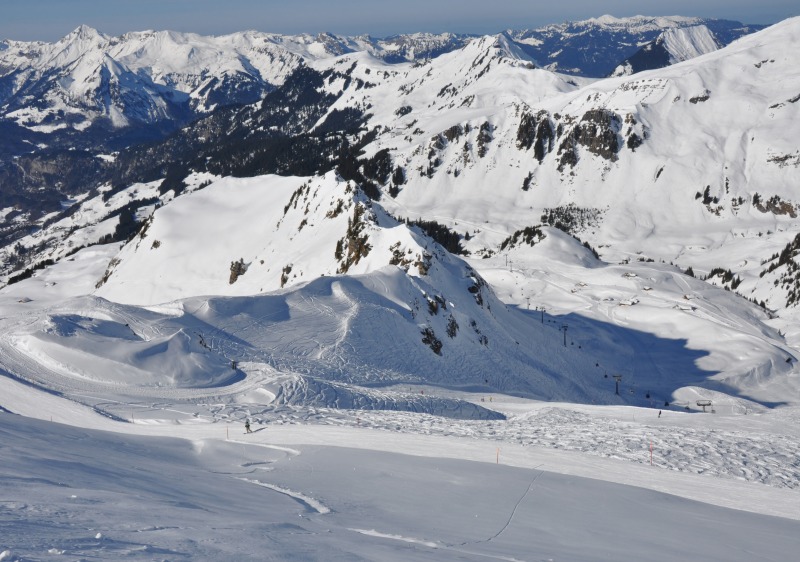 A Swiss chalet overlooks the bustling ski resort of Meiringen Hasliberg in Bern Switzerland framed by a stunning wintersports scene of skiers enjoying the snow-covered slopes.