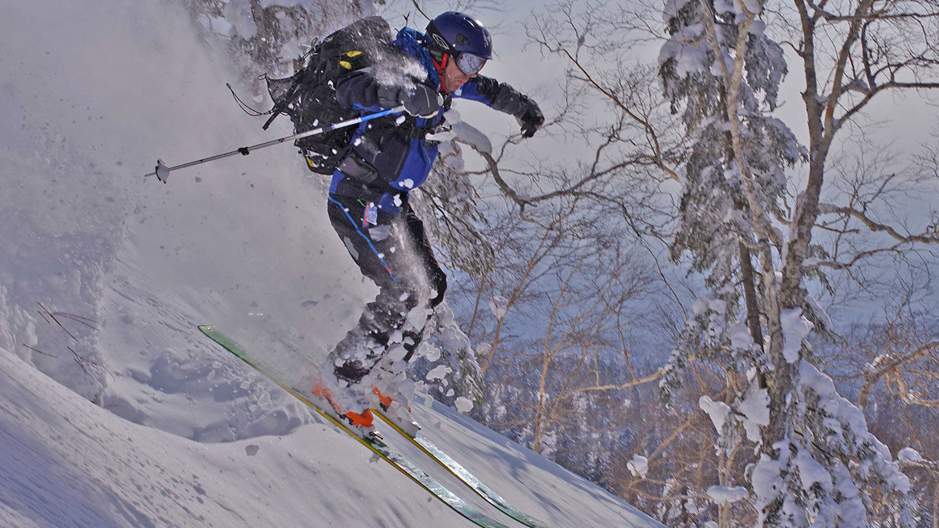 Asahi in Japan - a person skiing down a snowy slope in the mountains.