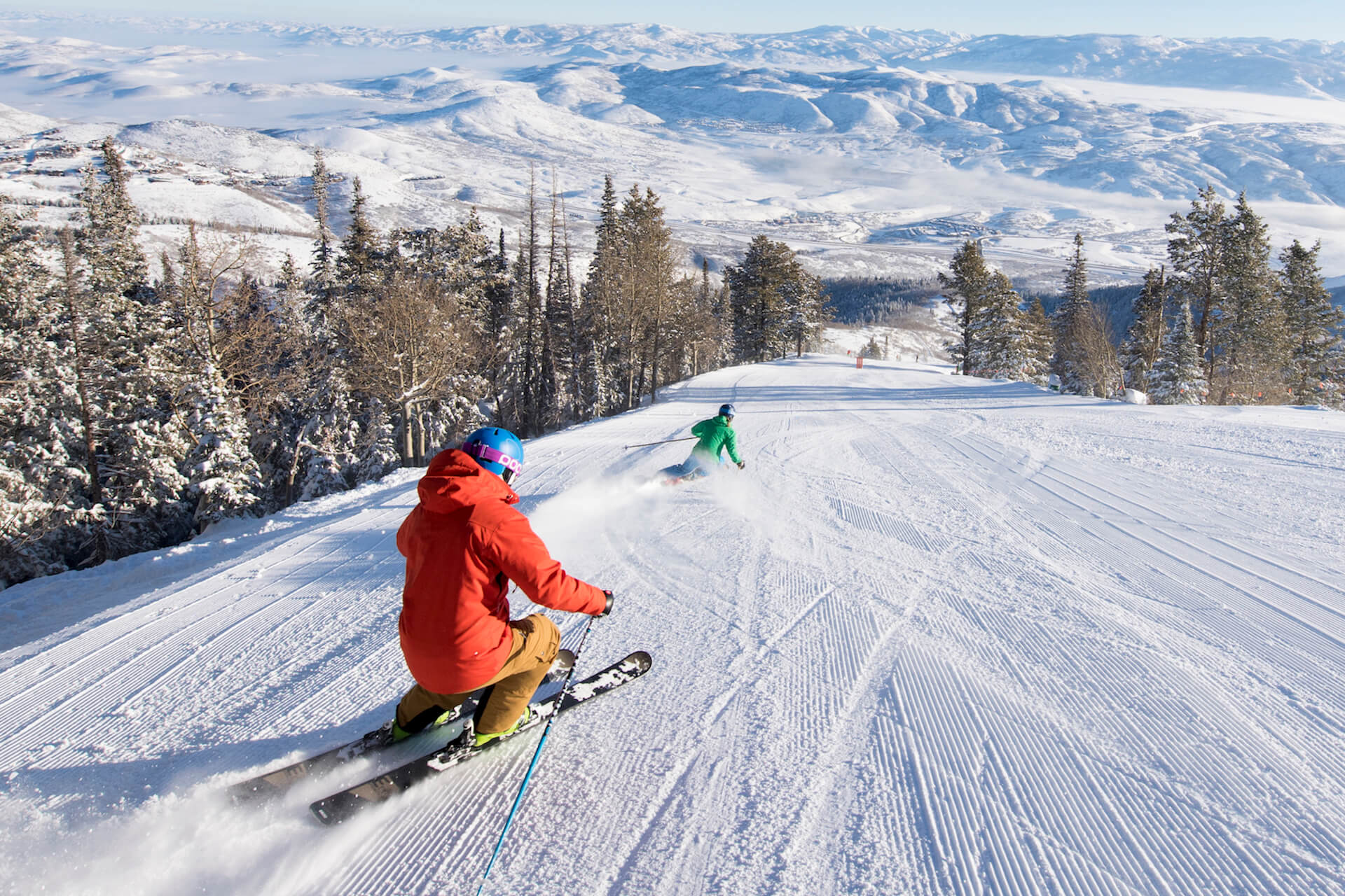 A winter sports scene at Snow Snake ski resort in Michigan USA featuring a skier carving down the snow-covered slope with a glimpse of a ski lift in the background.